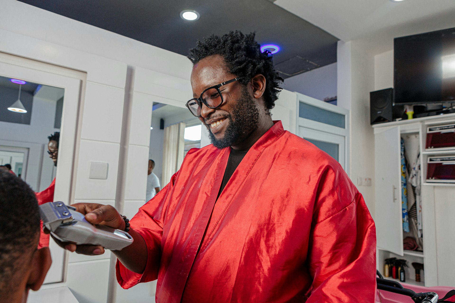 Barber shop a man in a red robe smiles as he holds a clipboard